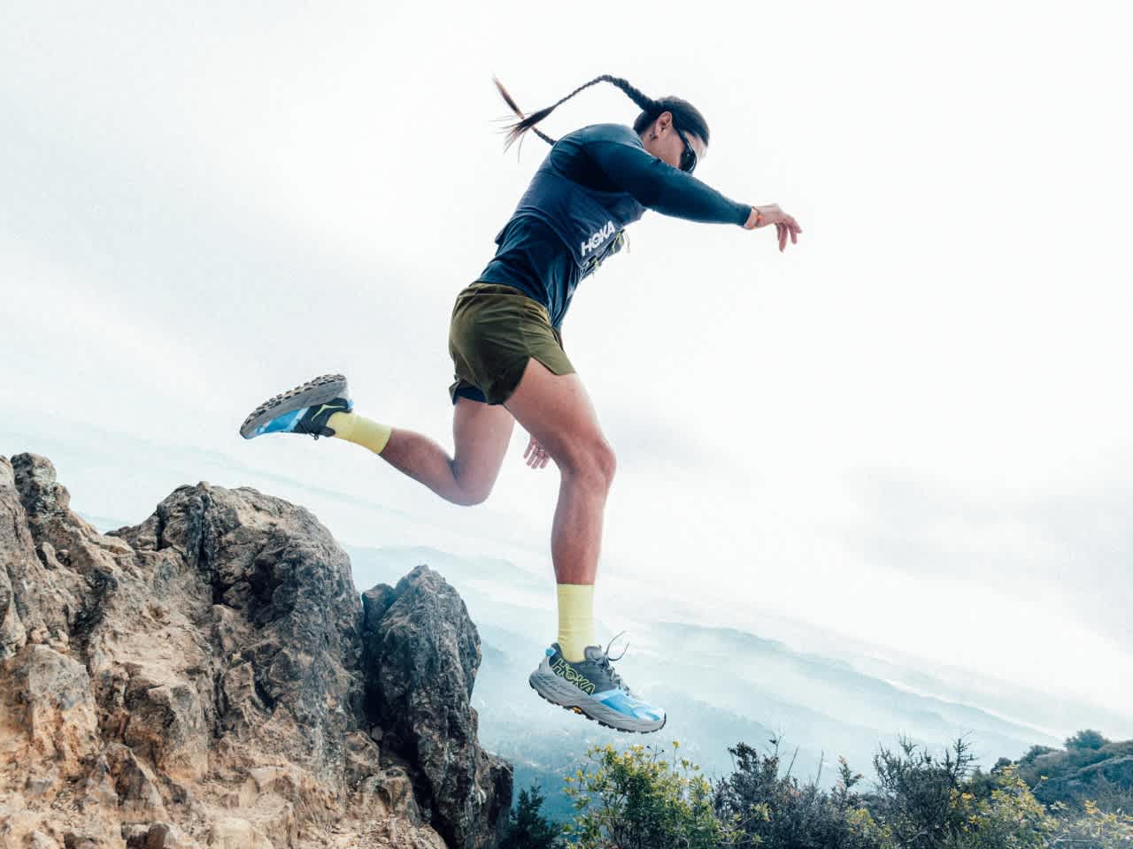 Action shot of a trail runner running down mountainous terrain