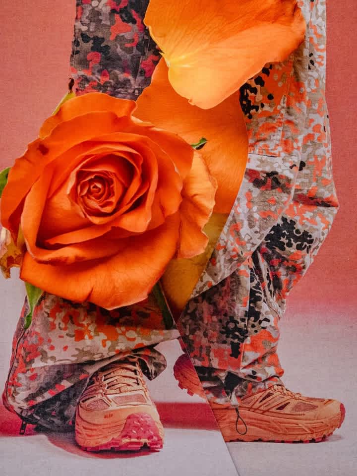 Lower legs in orange camo pants & peach sneakers, adorned with large orange roses.