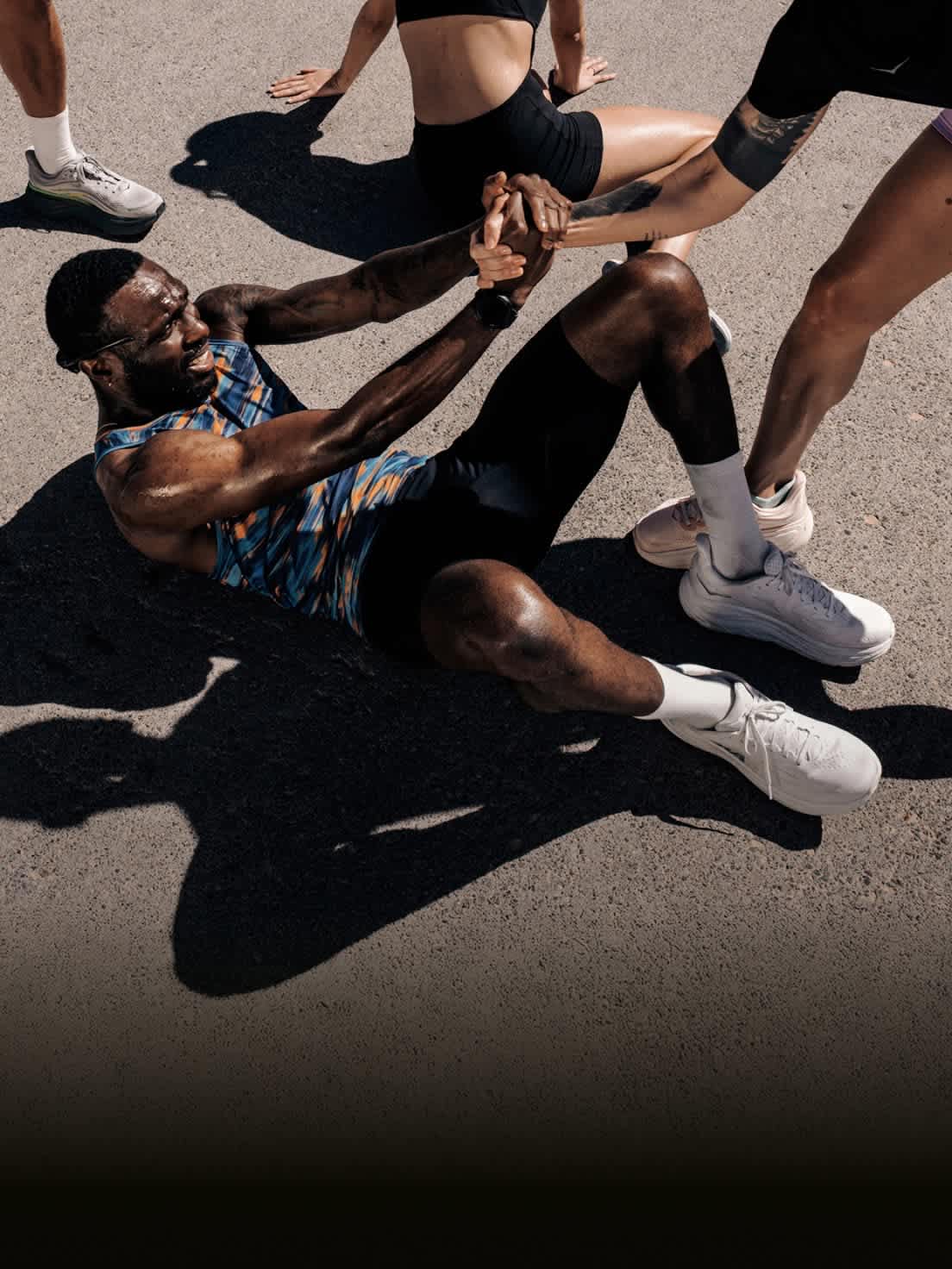 Sweaty individual on ground holding hands with two others pulling them up.