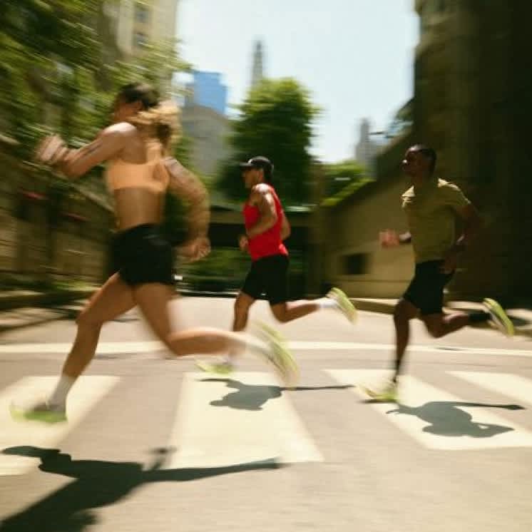 3 runners cross a pedestrian crossing on a city street.