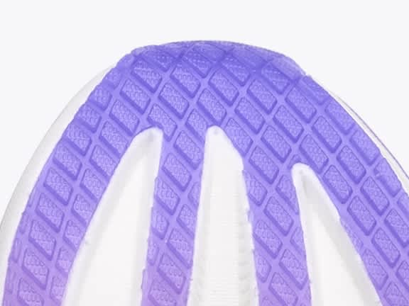 Close-up of a purple shoe sole with a textured pattern and white grooves.