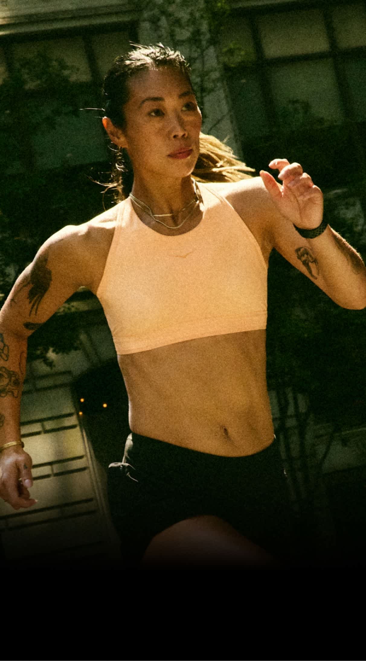 Person running outdoors in a peach sports bra and black shorts. 