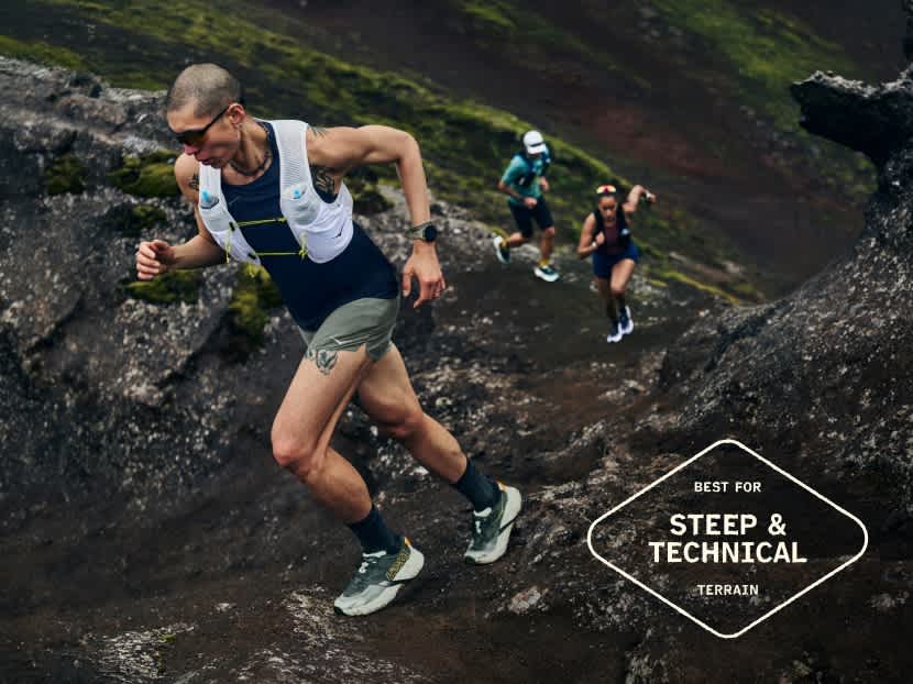 Three individuals trail running uphill on steep, rocky, technical terrain.