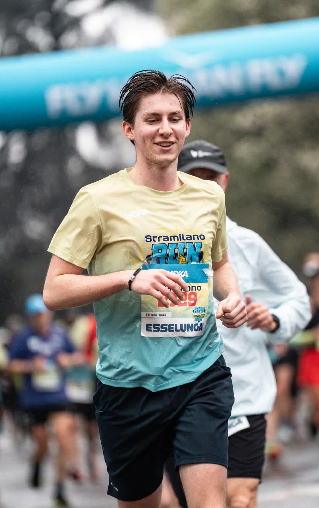 Smiling runner in two-tone race shirt with bib 29, blurred race background.
