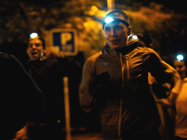 Runners with headlamps active at night in an urban environment.