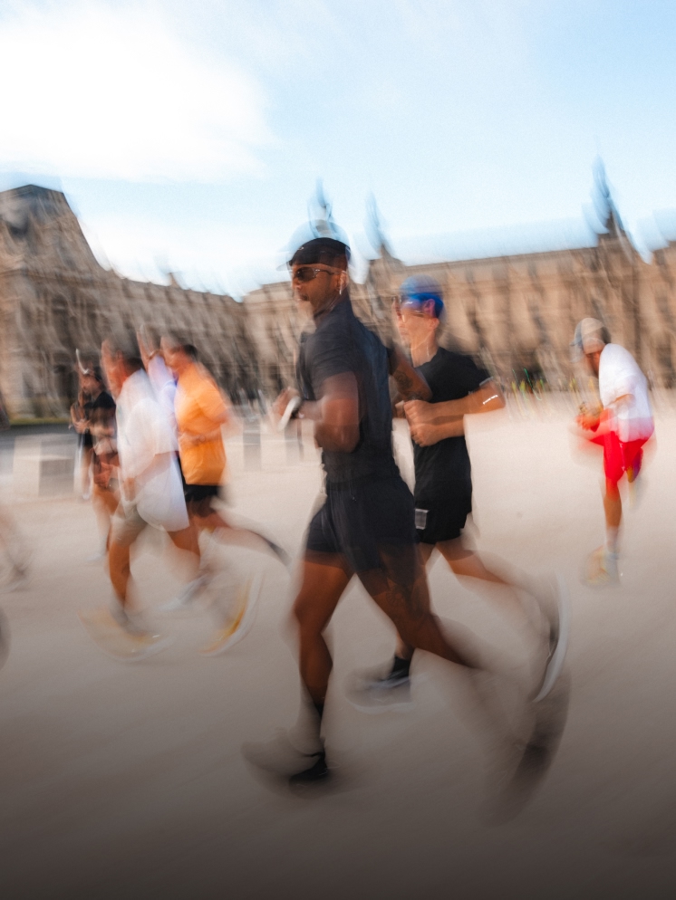 Motion-blurred image of several runners on a path by a large stone building.