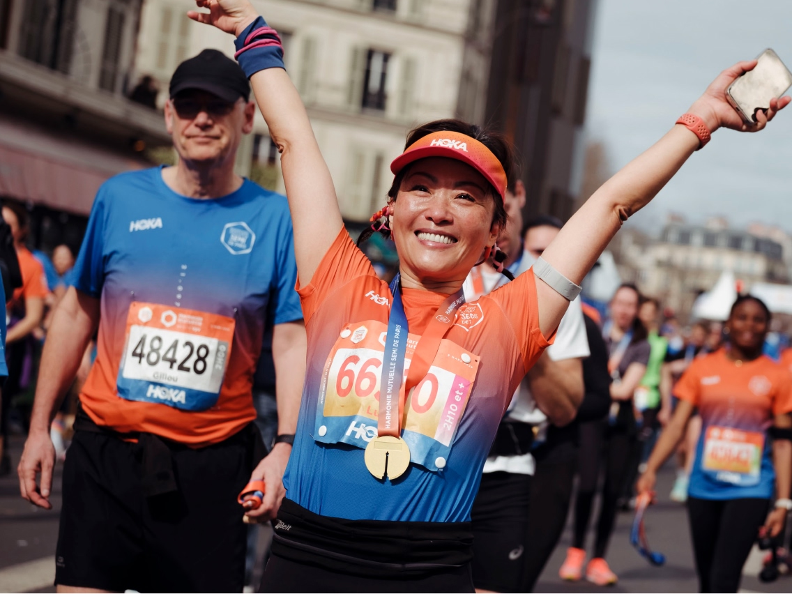 Smiling runner with bib 40556 taking water from volunteer at race aid station.
