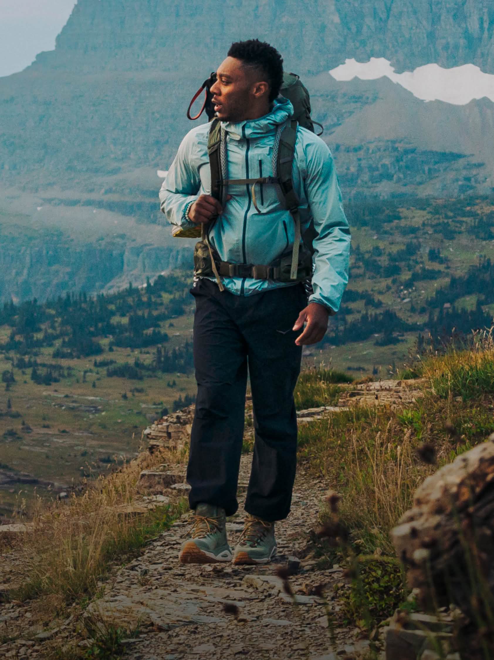 A male hiker admires the view on a mountainous walking path.