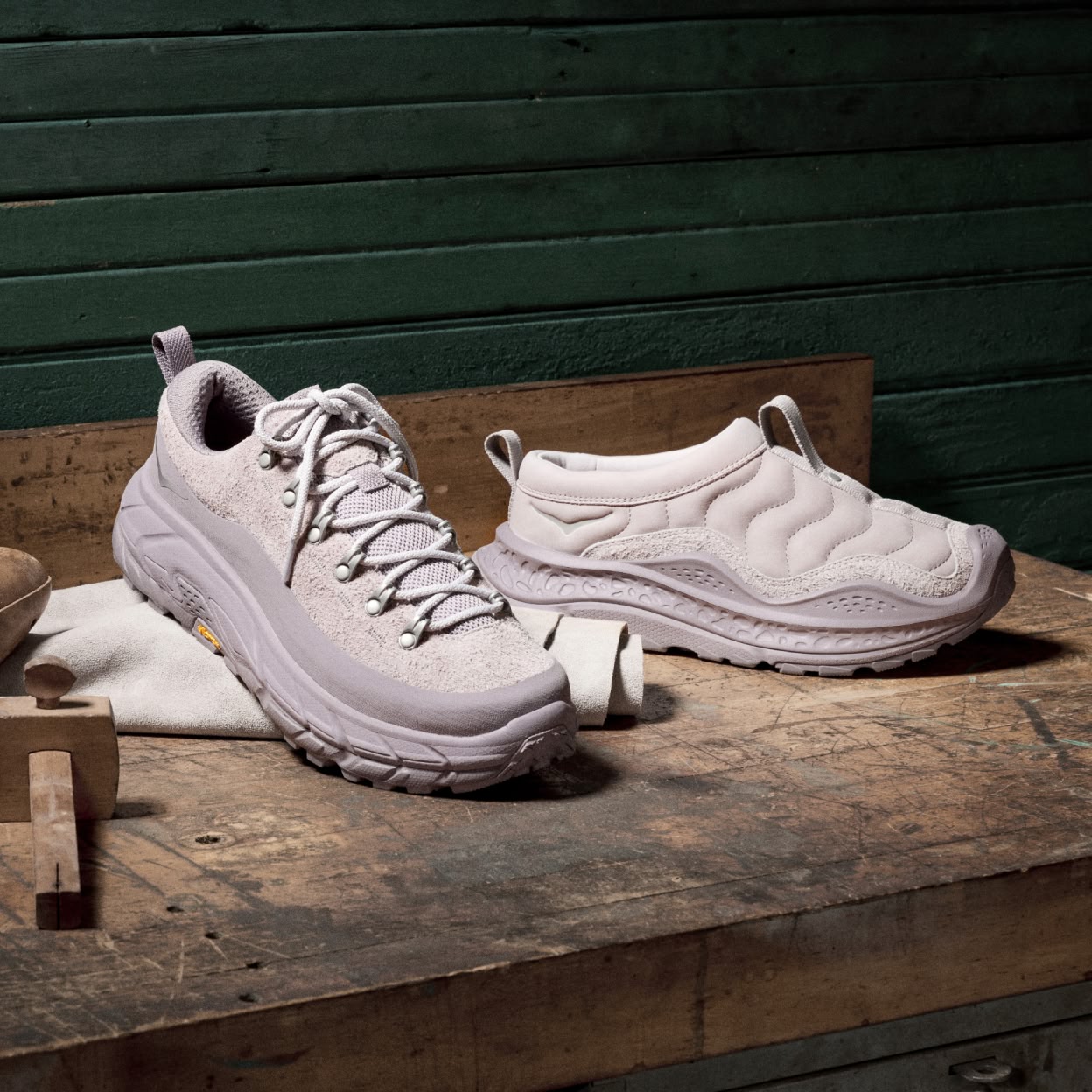 Two shoes sit on a table under a spotlight in a workshop-type setting.