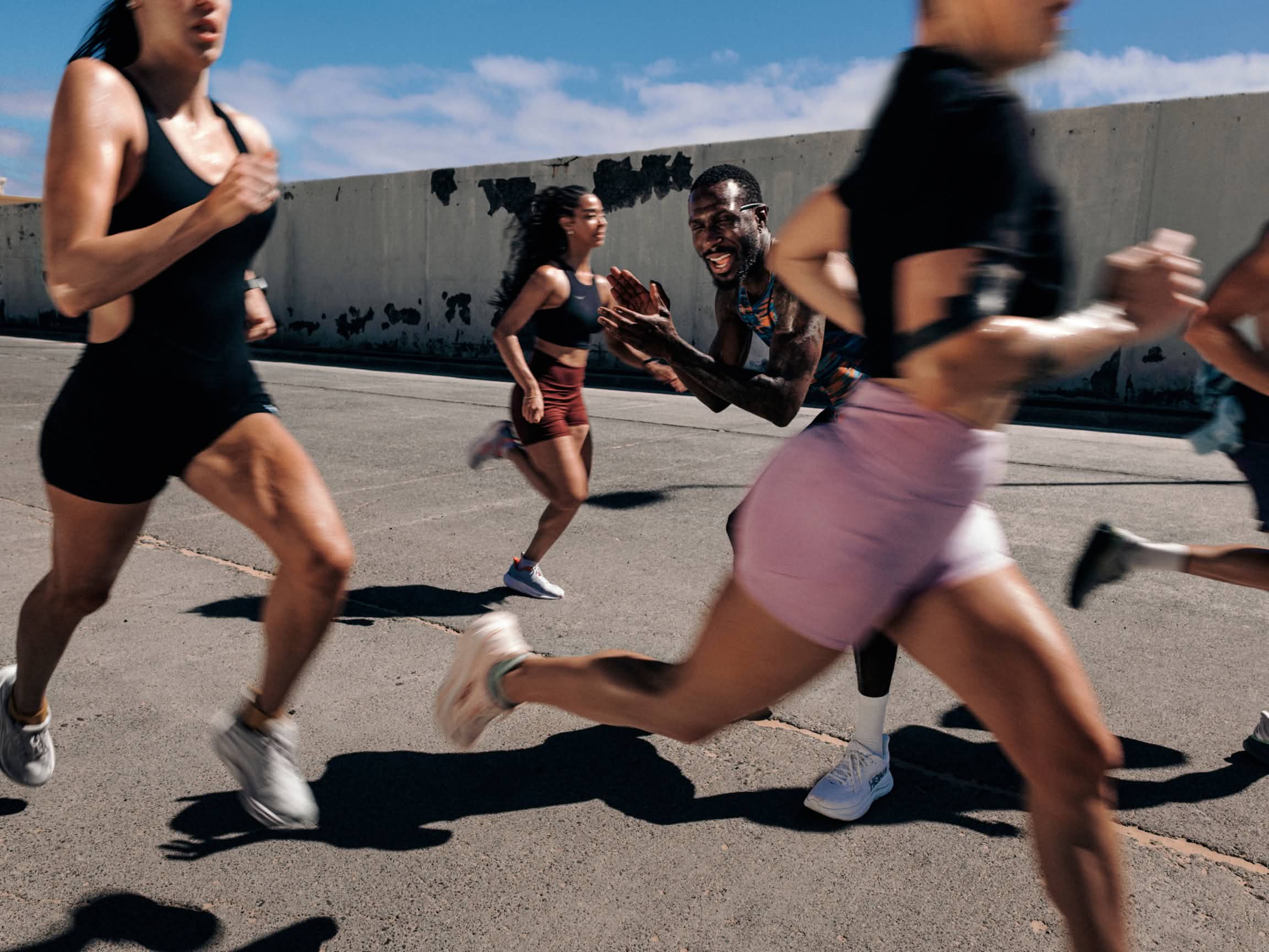Smiling runner in sunglasses high-fiving hands on a race course. Bib 0023.