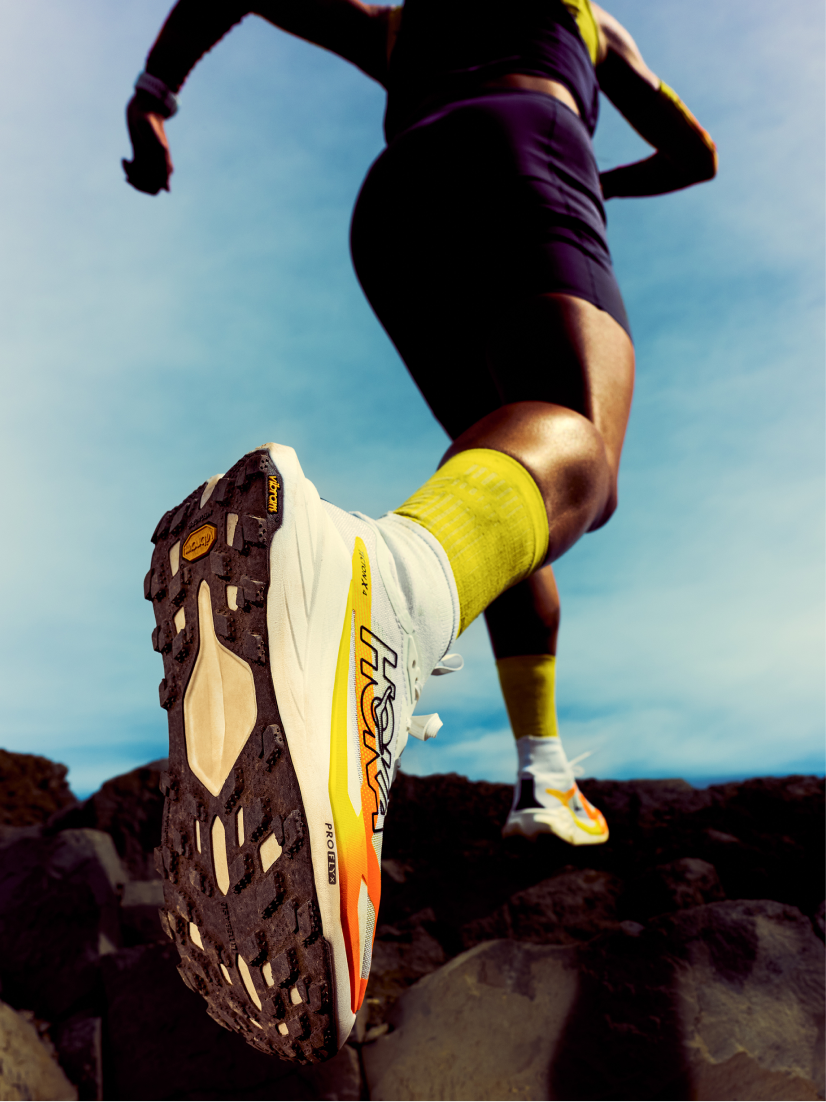 Stylish urban walker in HOKA sneakers strides through a city street with confidence and energy.