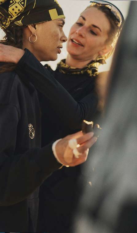 A close-up of two women in athletic gear smiling and embracing.