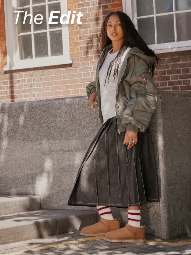 UGG boots styled with striped socks, midi skirt and bomber jacket outside.