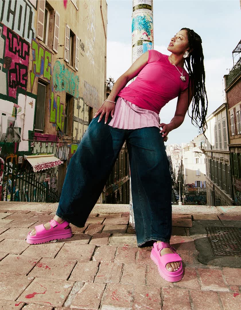 A person shot against an urban graffiti background, wearing Goldenstrap sandal.