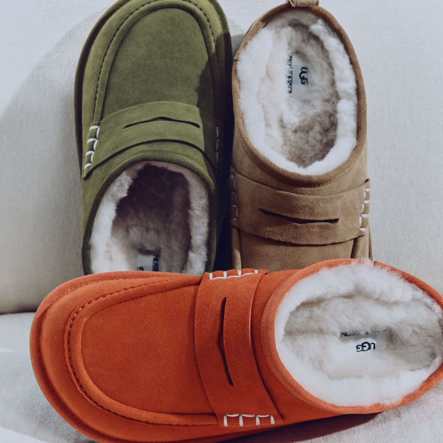 A studio shot of UGG JW Anderson loafers in khaki, chestnut and orange.