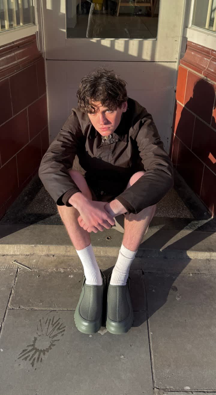 A person sitting on a step in the sunshine wearing shorts and white socks with the PeakMod.