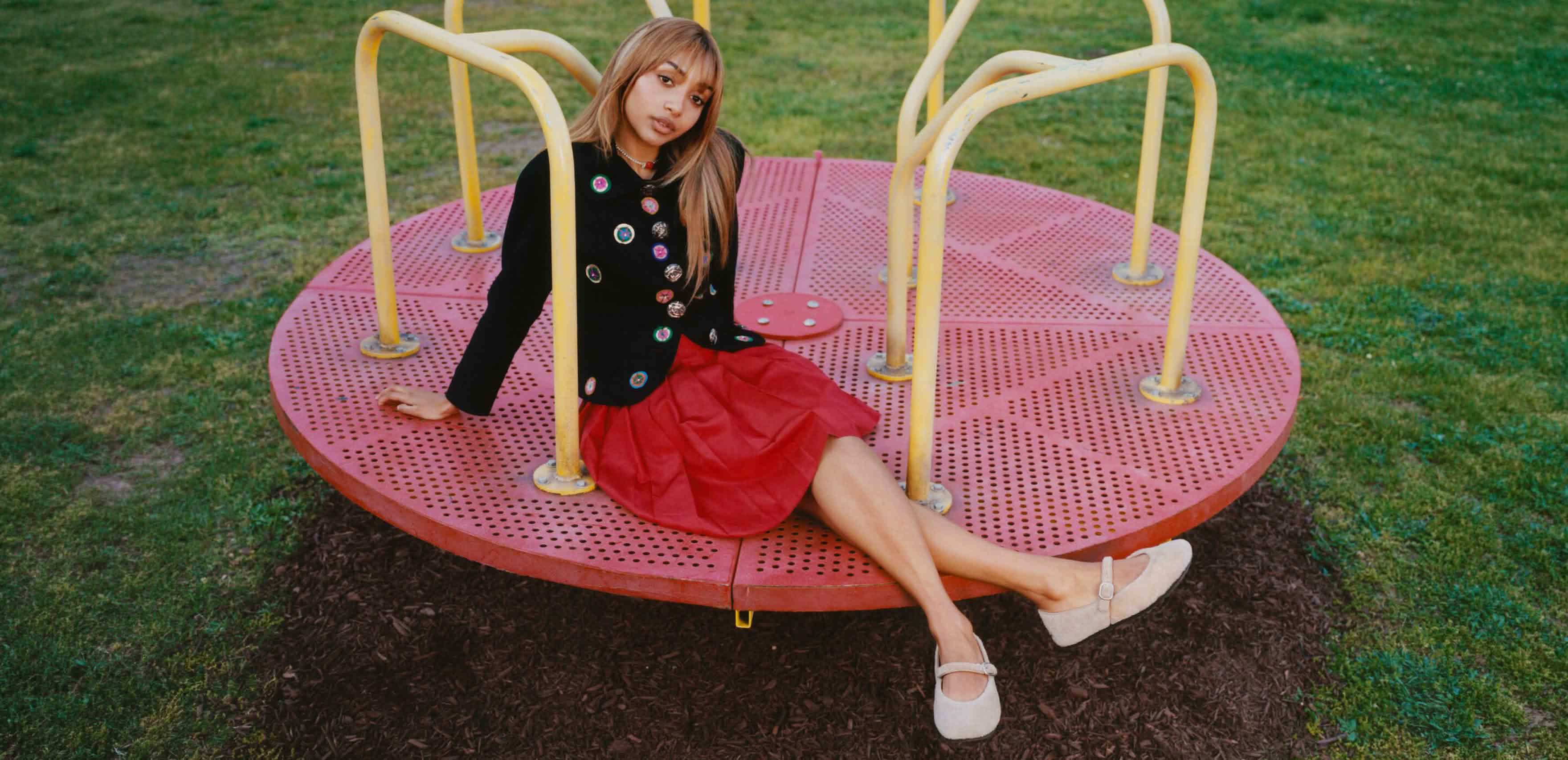 UGG cream suede Mary Jane shoes worn on a playground roundabout with a red skirt.