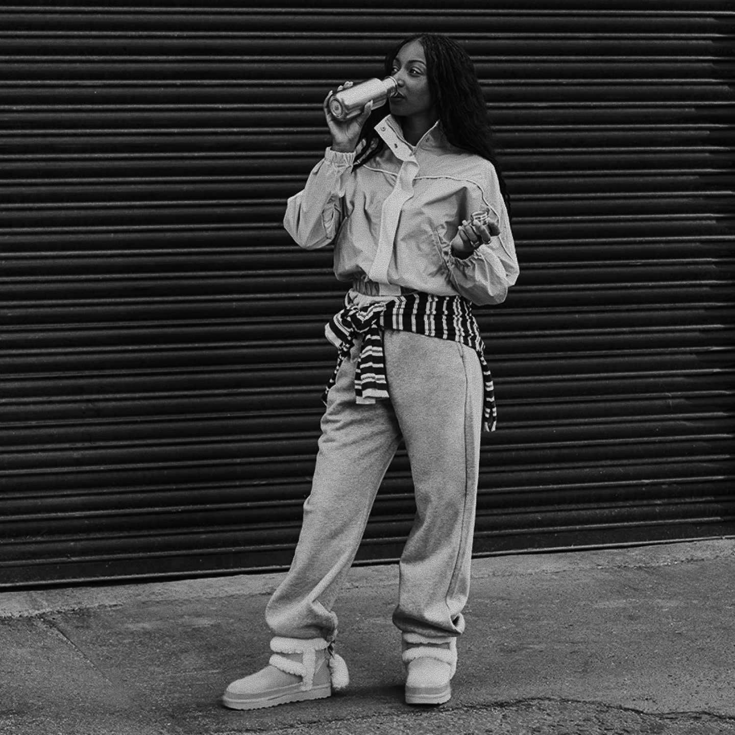 Person in jacket & sweatpants drinking, wearing Classic Mini Heritage Boots.