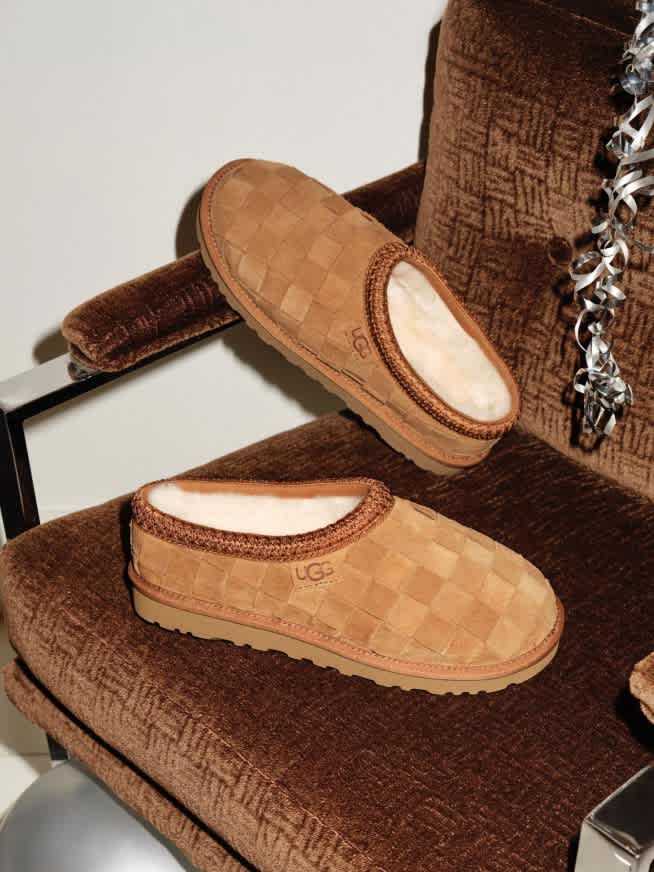 Two UGG checkered slippers on a brown armchair with silver balloon and confetti.
