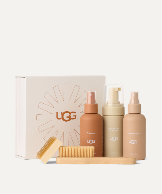 Studio shot of the UGG Clean and Care Kit with three bottles—Protector, Cleaner and Conditioner, Shoe Renew—plus two brushes and a box.